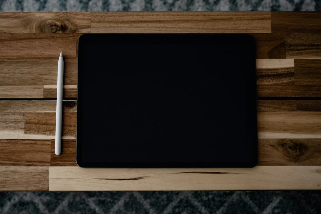 iPad e Apple Pencil fotografados sobre uma mesa de madeira